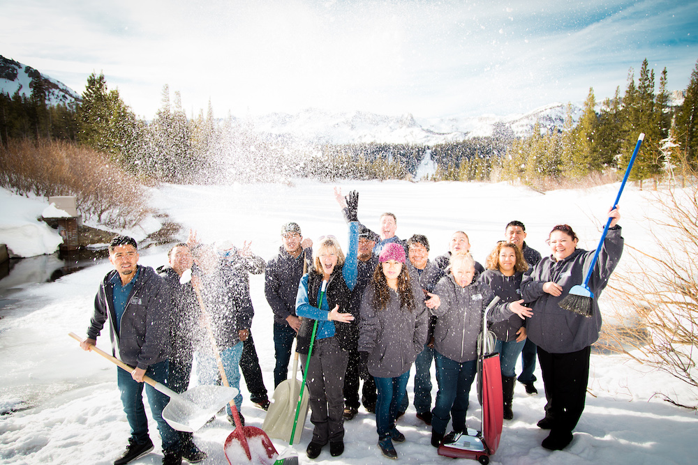 the entire Perfect Clean Inc. team poses and throws snow in front of a snowy and frozen Twin Lakes in Mammoth Lakes, California